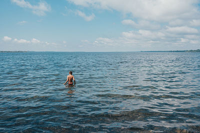 Tween boy wading in lake ontario on a summer day.