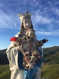 Virgin mary and jesus christ statue on field against sky