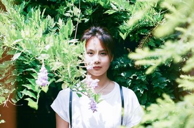 Portrait of woman standing amidst trees