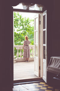 Rear view of woman standing in balcony at home