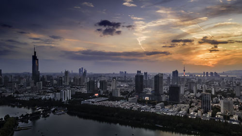 Aerial view of buildings against cloudy sky during sunset