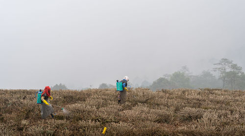 Rear view of woman walking on field against clear sky