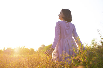 Woman standing on field against sky