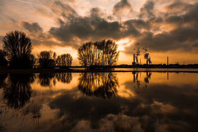 Silhouette trees by lake against sky during sunset