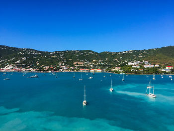 Sailboats in sea against clear blue sky