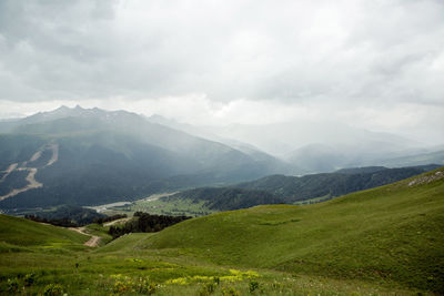 Green slope of a high mountain during a thunderstorm with clouds in the sky