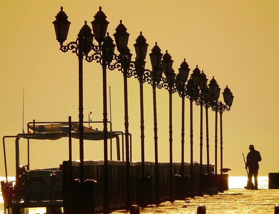 sky, sunset, real people, architecture, silhouette, nature, lifestyles, water, built structure, one person, clear sky, men, leisure activity, orange color, sea, outdoors, full length, standing, architectural column