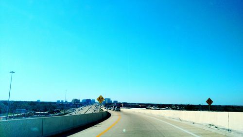 Cars on road against clear blue sky