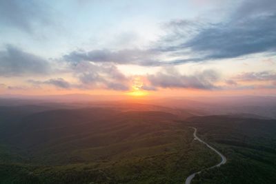 Scenic view of landscape against dramatic sky during sunset