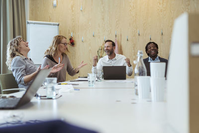 Happy business professionals cheering in meeting at office