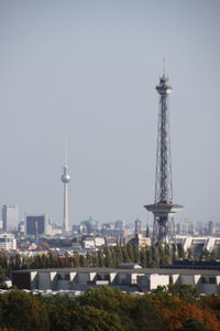 Communications tower in city against clear sky