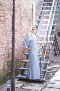 Portrait of woman standing against brick wall