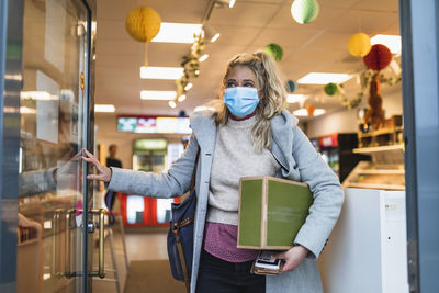 Female customer carrying package while leaving store during covid-19