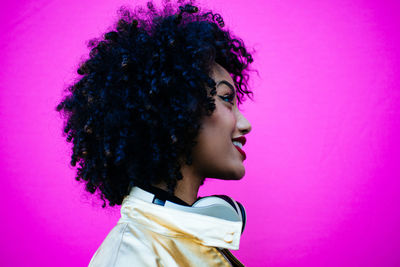 Close-up of young woman with frizzy hair against pink background