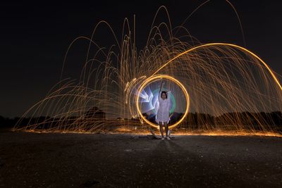 Full length of woman with wire wool against sky at night