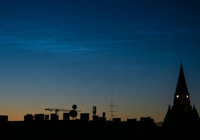 Silhouette of buildings against sky with noctilucent clouds during sunset