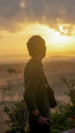 Man standing by sea against sky during sunset