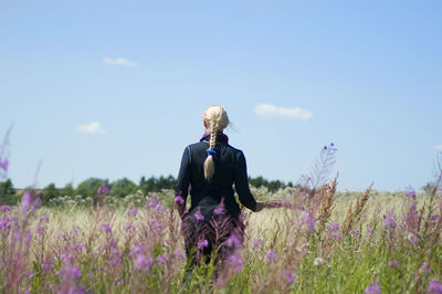 Back view of caucasian blonde woman in thermal suit on blooming sally meadow