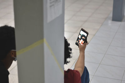 Low section of man and woman photographing with mobile phone on floor