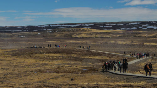 People walking on landscape against sky