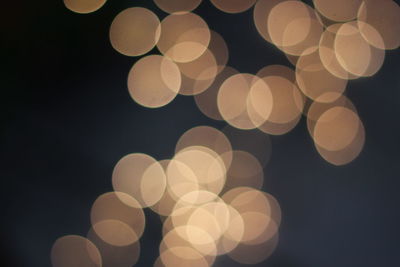 Defocused image of illuminated lights against sky at night