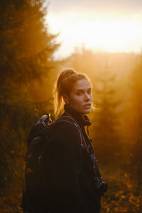 Portrait of woman standing in forest during sunset