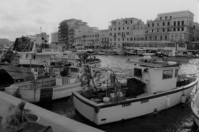 Boats moored in harbor against buildings in city