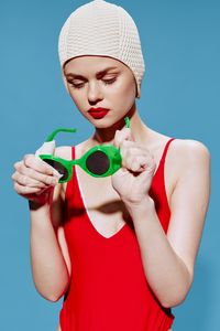 Portrait of smiling young woman wearing hat against blue background