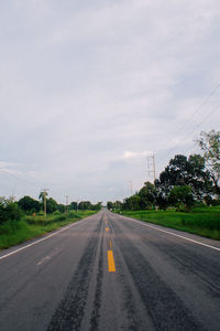 Road by trees against sky