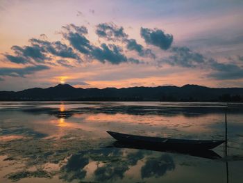 Boat moored at river against sky during sunset