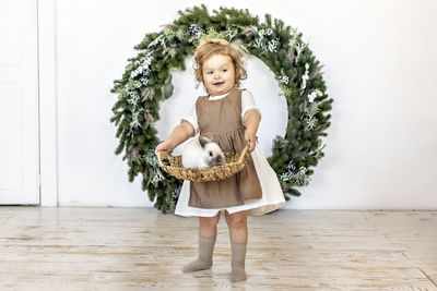 A little girl is holding a basket with a rabbit on the background of christmas decorations. new year