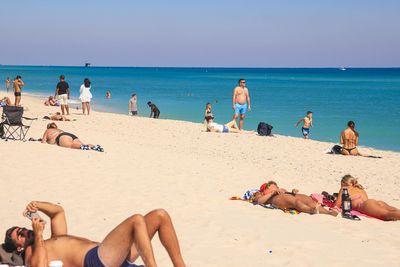 People at beach against clear sky