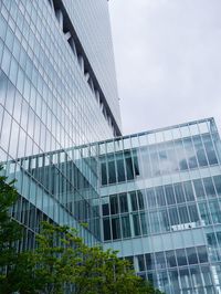 Low angle view of modern glass building against sky