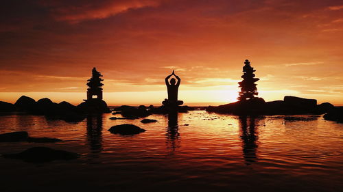 Silhouette person doing yoga at sea against sky during sunset