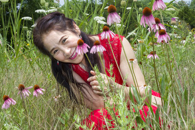 Portrait of smiling woman with flowers in field