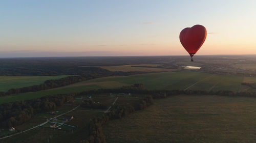 Hot air balloons flying over landscape against sky during sunset