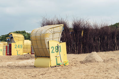 Hooded chairs on beach against sky