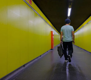 Rear view of man walking on illuminated subway station