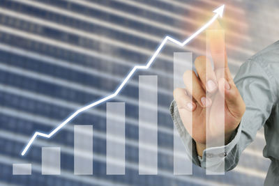 Digital composite image of businessman touching graph on device screen
