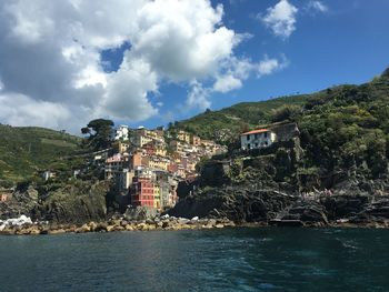 Buildings by sea against sky