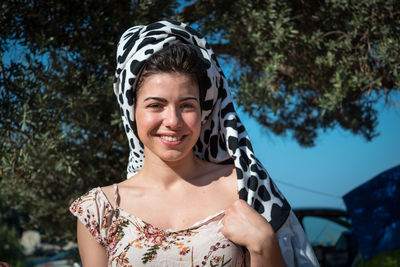 Portrait of smiling young woman against trees