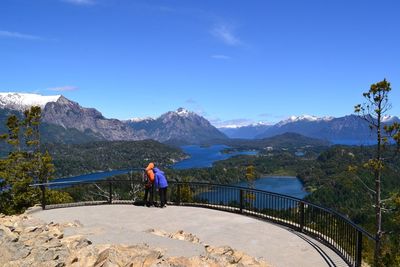 Rear view of people at observation point by mountains against sky