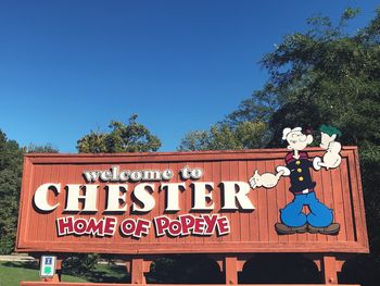 Low angle view of information sign against clear blue sky