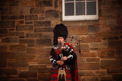 Portrait of man with instrument against wall