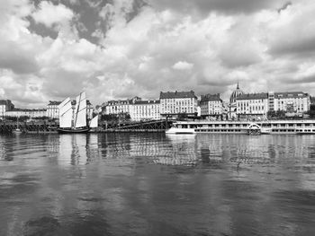 Buildings by river against sky in city