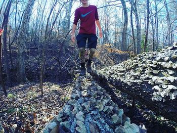 Man standing on tree trunk in forest