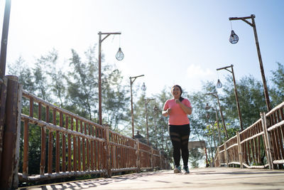 Full length of young woman standing on railing