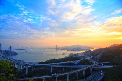 Road by bridge in city against sky during sunset