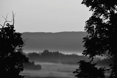 Silhouette trees on landscape against sky