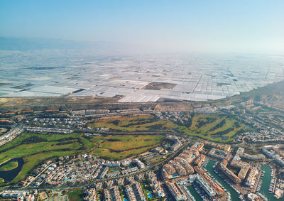 Aerial view of agricultural field by buildings against sky